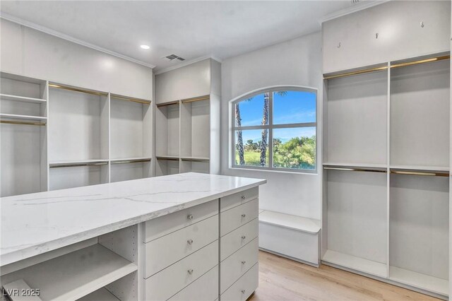 walk in closet with light hardwood / wood-style floors