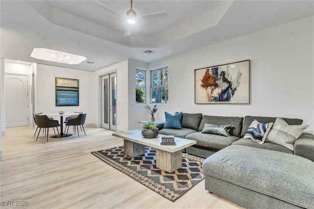 living room featuring a tray ceiling and light hardwood / wood-style flooring