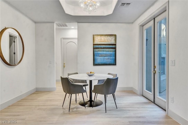 dining area featuring a notable chandelier, light hardwood / wood-style floors, and french doors