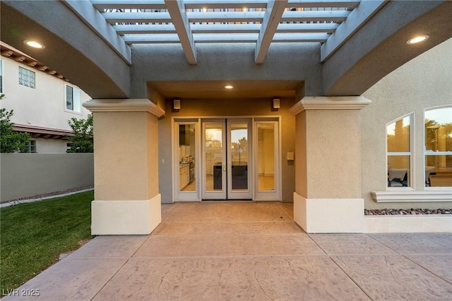 view of exterior entry with a pergola and a patio