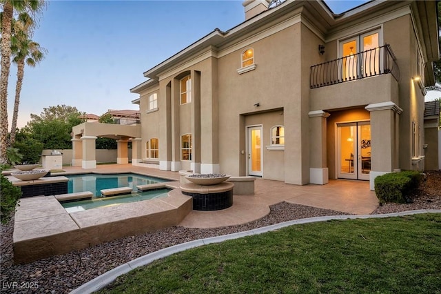 rear view of property featuring a patio, a balcony, and an in ground hot tub