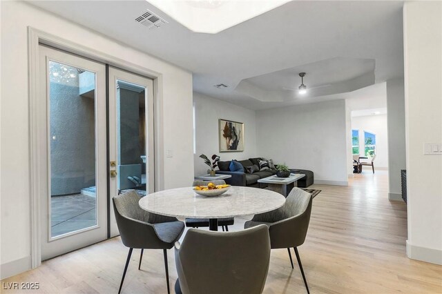 dining area with light hardwood / wood-style flooring and a raised ceiling