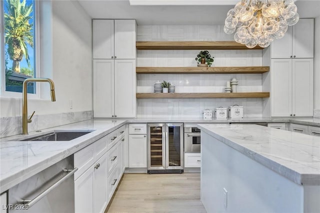 kitchen with light stone counters, wine cooler, open shelves, white cabinets, and a sink