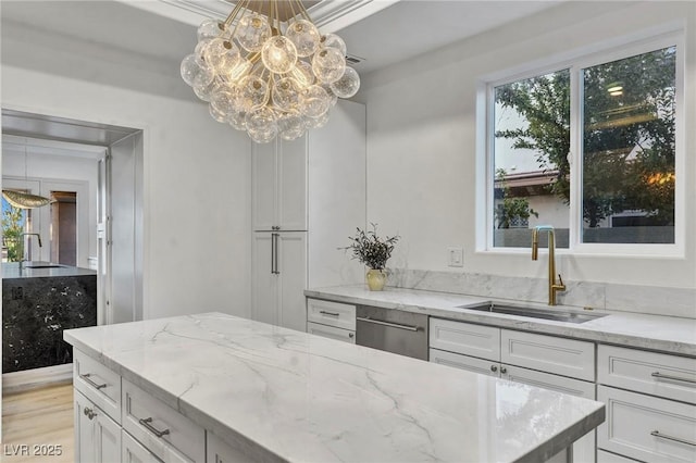 kitchen with white cabinetry, a sink, and light stone countertops