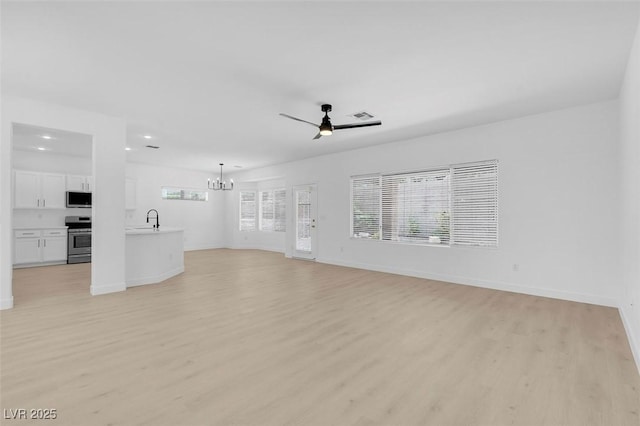 unfurnished living room featuring sink, ceiling fan with notable chandelier, and light hardwood / wood-style flooring