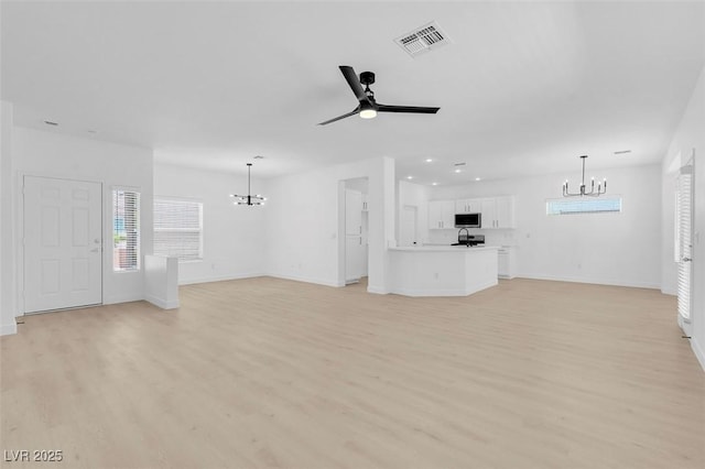 unfurnished living room with ceiling fan with notable chandelier and light wood-type flooring