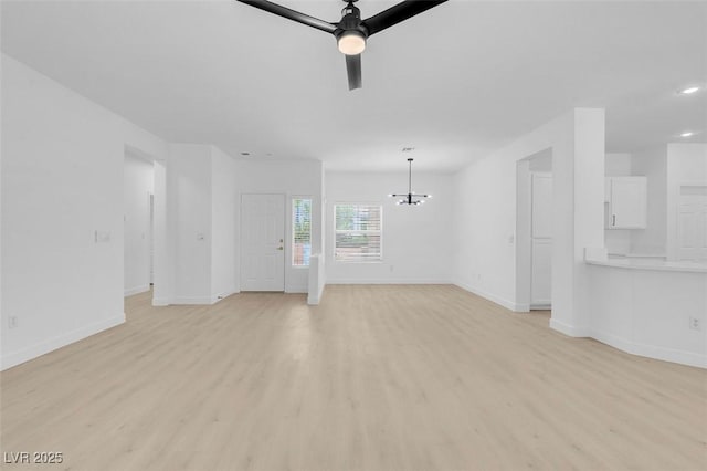 unfurnished living room featuring ceiling fan with notable chandelier and light hardwood / wood-style flooring