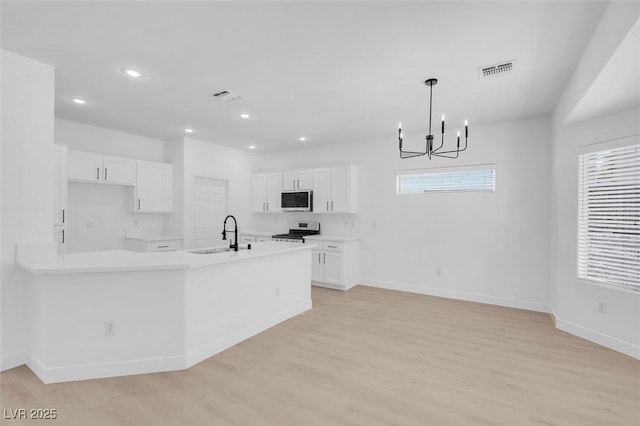 kitchen with sink, pendant lighting, a notable chandelier, electric stove, and white cabinets