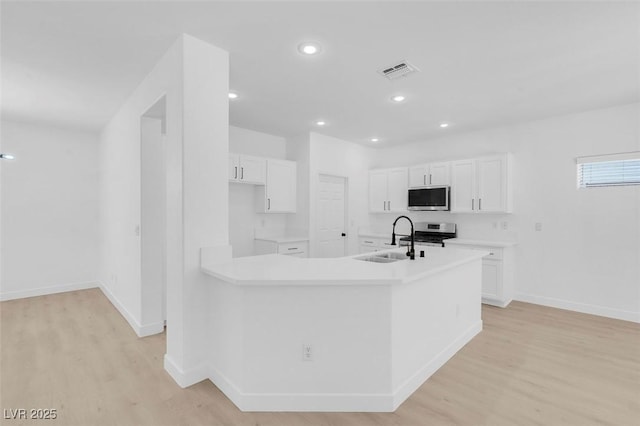 kitchen featuring appliances with stainless steel finishes, sink, white cabinets, and light hardwood / wood-style flooring