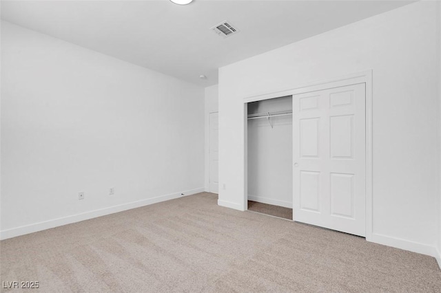 unfurnished bedroom with light colored carpet and a closet