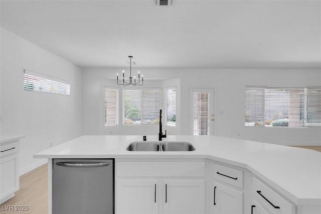 kitchen featuring sink, white cabinets, hanging light fixtures, stainless steel dishwasher, and light hardwood / wood-style floors