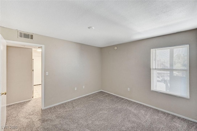 spare room with light colored carpet and a textured ceiling