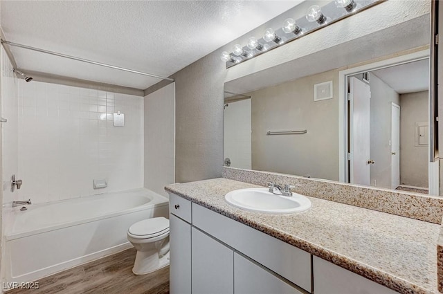 full bathroom with toilet, wood-type flooring, a textured ceiling, vanity, and tiled shower / bath combo