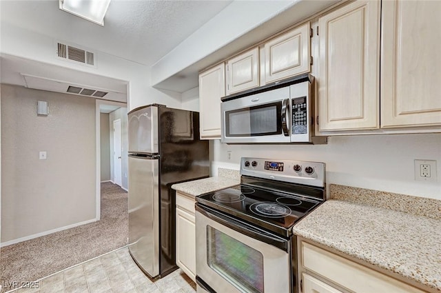 kitchen featuring stainless steel appliances, light carpet, a textured ceiling, and light stone counters