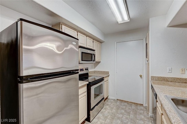 kitchen with appliances with stainless steel finishes, light stone countertops, sink, and a textured ceiling