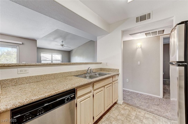 kitchen with sink, light colored carpet, light stone counters, ceiling fan, and stainless steel appliances