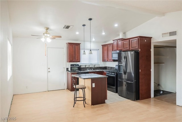 kitchen featuring pendant lighting, stove, a kitchen island, fridge with ice dispenser, and a kitchen bar