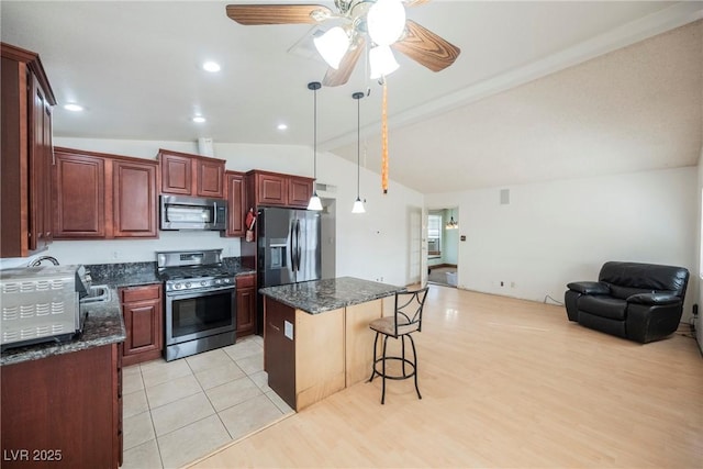 kitchen with vaulted ceiling with beams, dark stone counters, a kitchen breakfast bar, a kitchen island, and stainless steel appliances