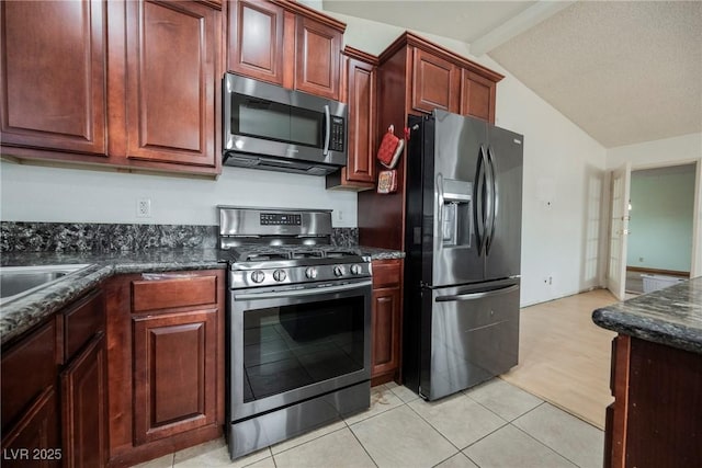 kitchen featuring stainless steel appliances, lofted ceiling with beams, a textured ceiling, and dark stone countertops