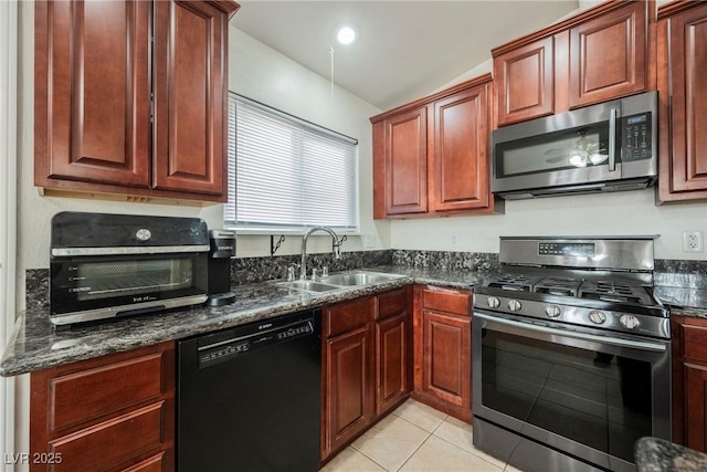 kitchen featuring dark stone countertops, stainless steel appliances, sink, and light tile patterned floors