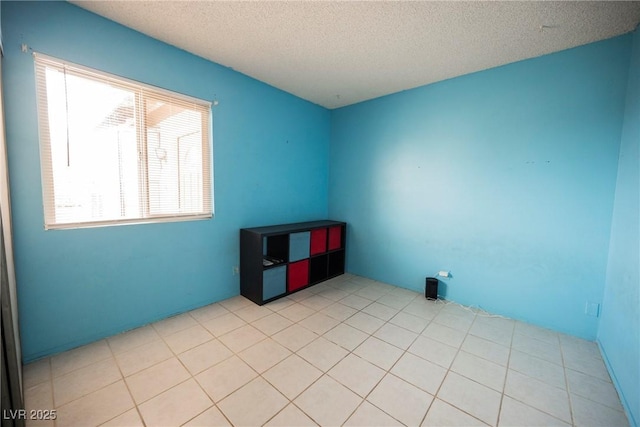 spare room with a textured ceiling and light tile patterned floors