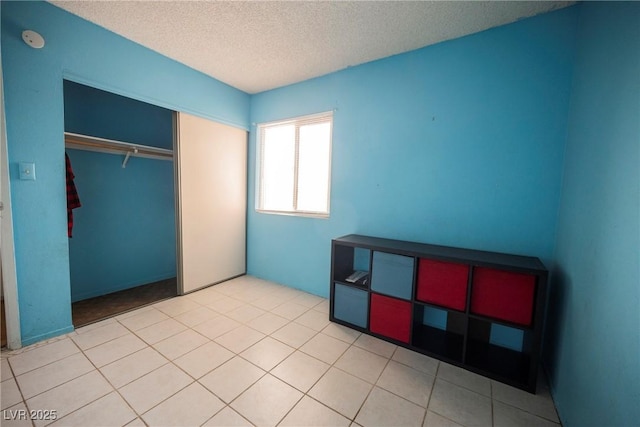 tiled bedroom with a closet and a textured ceiling