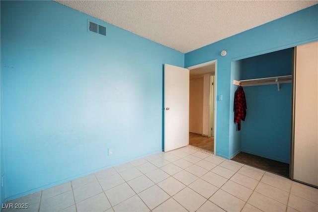 unfurnished bedroom featuring light tile patterned floors, a closet, and a textured ceiling