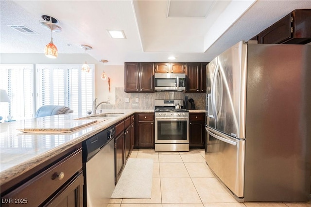 kitchen featuring sink, hanging light fixtures, light tile patterned floors, stainless steel appliances, and backsplash