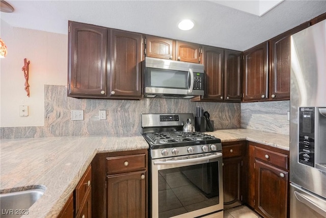 kitchen with tasteful backsplash, light tile patterned flooring, appliances with stainless steel finishes, and dark brown cabinetry