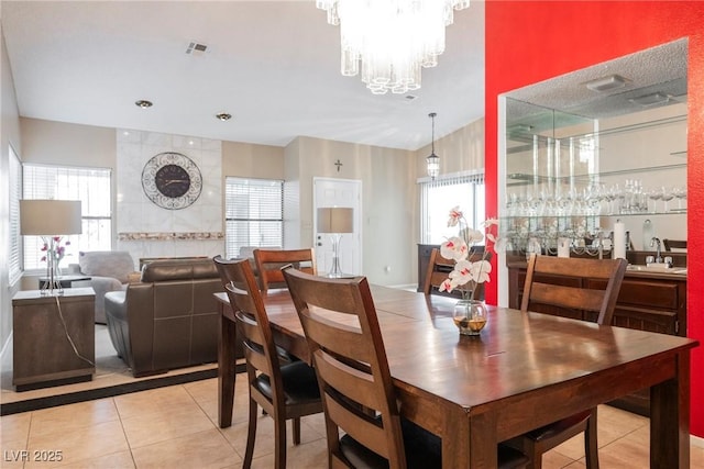 tiled dining space featuring a wealth of natural light, a notable chandelier, and indoor wet bar