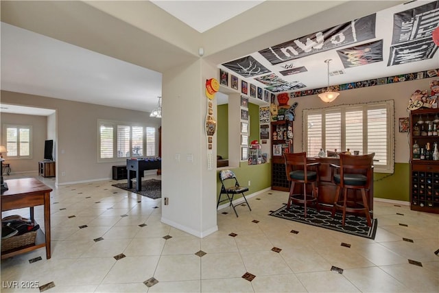 dining space featuring a dry bar, baseboards, and light tile patterned flooring