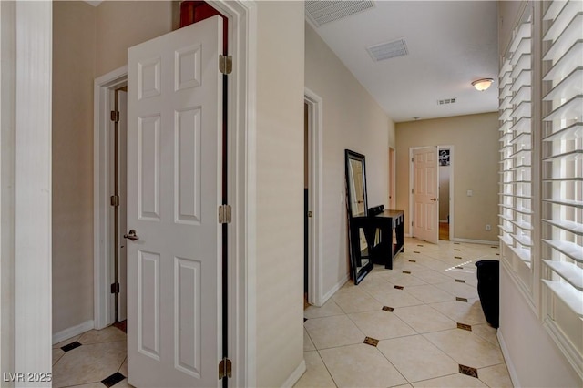 hall featuring light tile patterned flooring, visible vents, and baseboards