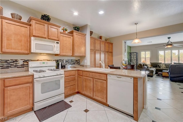 kitchen featuring white appliances, open floor plan, light countertops, pendant lighting, and a sink