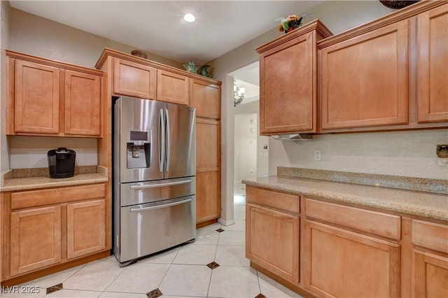 kitchen with light tile patterned floors, recessed lighting, stainless steel fridge, and light stone countertops