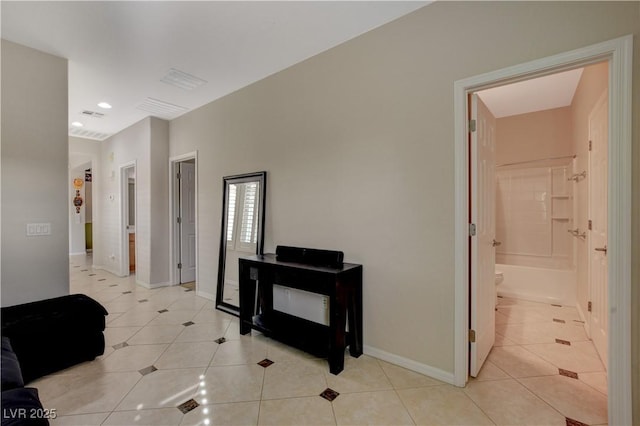 hallway featuring light tile patterned floors, visible vents, and baseboards