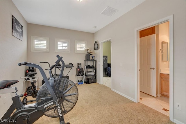 exercise area with light colored carpet, visible vents, baseboards, and light tile patterned floors