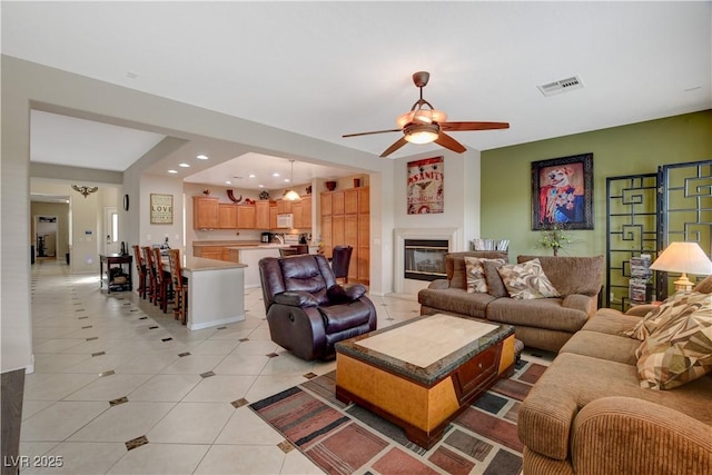 living area with light tile patterned floors, recessed lighting, visible vents, a ceiling fan, and a glass covered fireplace