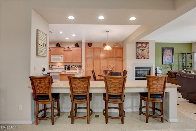 kitchen featuring white appliances, decorative backsplash, a breakfast bar, open floor plan, and hanging light fixtures