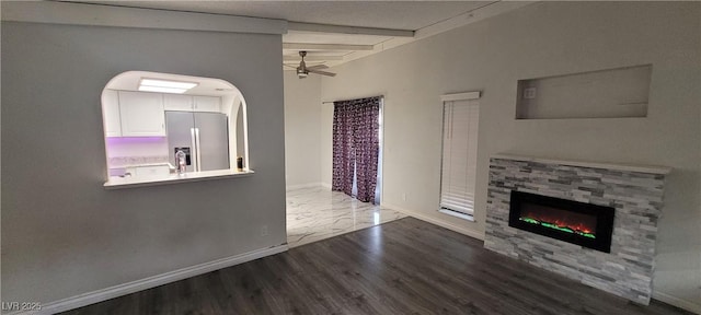 unfurnished living room with wood-type flooring, beamed ceiling, and ceiling fan