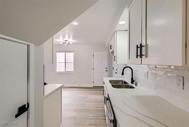 kitchen featuring white cabinetry, sink, decorative backsplash, light stone counters, and light wood-type flooring