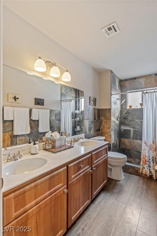 bathroom featuring wood-type flooring, tile walls, vanity, toilet, and a shower with shower curtain