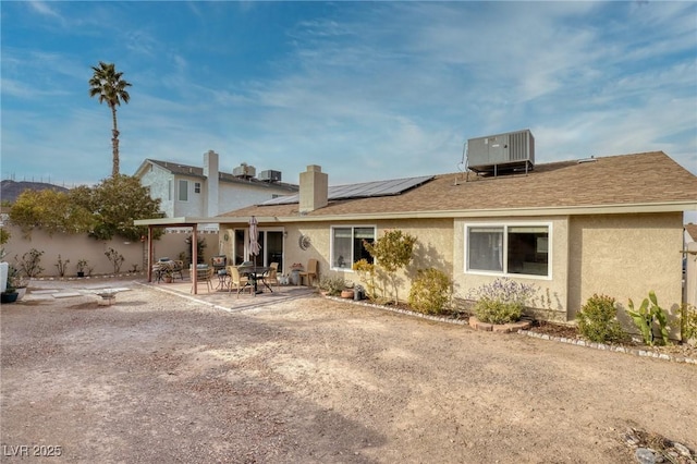 rear view of house featuring cooling unit, a patio area, and solar panels