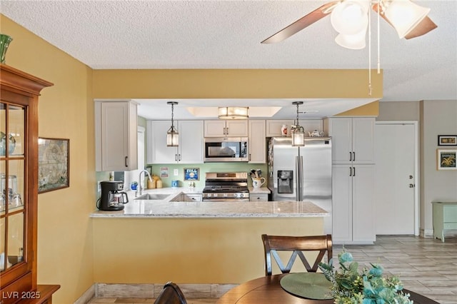 kitchen with sink, hanging light fixtures, appliances with stainless steel finishes, kitchen peninsula, and white cabinets