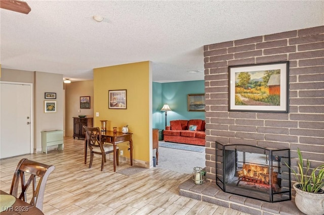 living room featuring a fireplace, a textured ceiling, and light wood-type flooring