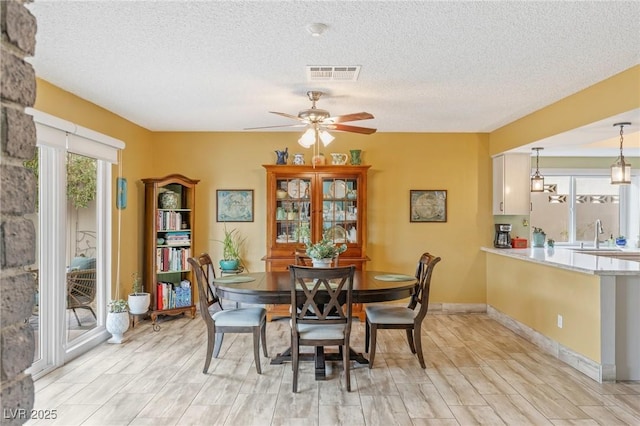 dining space featuring ceiling fan, sink, and a textured ceiling