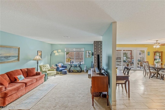 living room featuring ceiling fan, a brick fireplace, and a textured ceiling