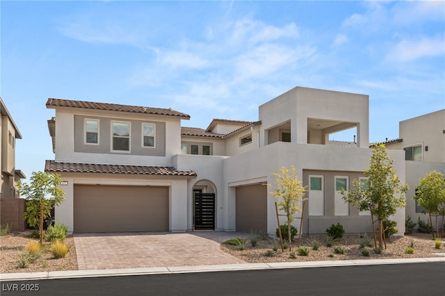 view of front facade featuring a garage, decorative driveway, a tiled roof, and stucco siding