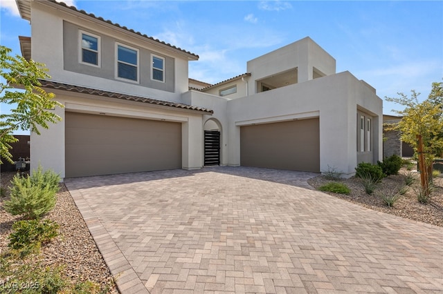 view of front of house featuring a garage, decorative driveway, a tiled roof, and stucco siding