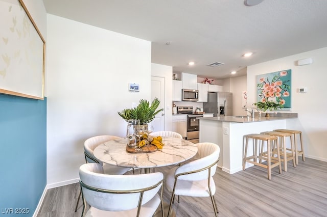 dining area with sink and light hardwood / wood-style floors