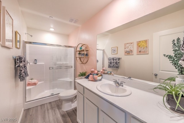 bathroom with an enclosed shower, vanity, wood-type flooring, and toilet